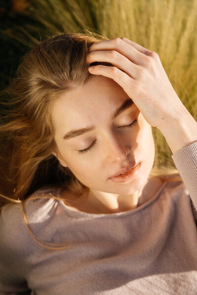  girl lies in a field on the grass, enjoys the sun