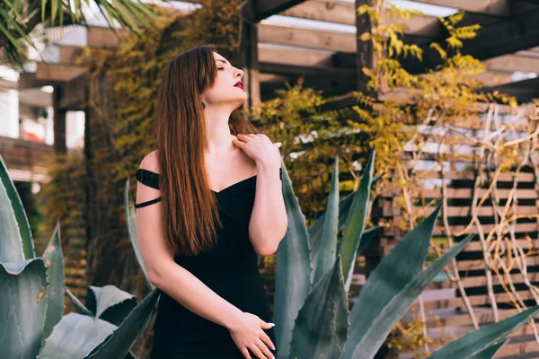 Mujer en un vestido negro descansando en su jardín — Foto de Stock