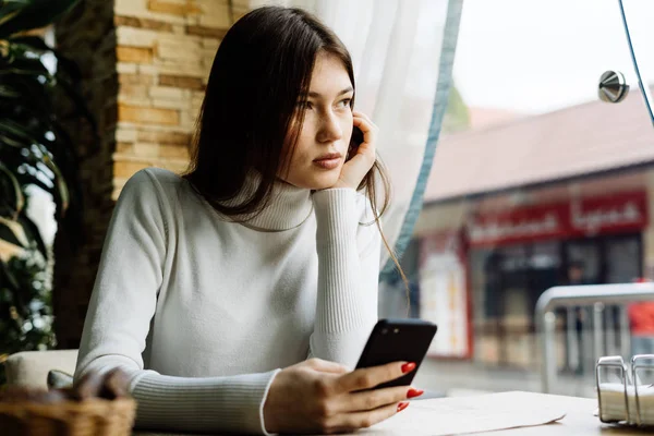 Young beautiful brunette girl sitting in a cafe — Stock Photo, Image