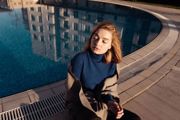 Meisje zit bij het zwembad, geniet van de zon, de ogen gesloten — Stockfoto
