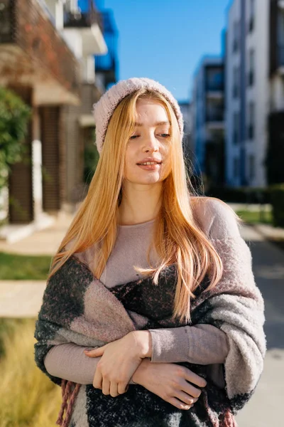 Ung vacker blond flicka i hatt och varm halsduk gå genom gatorna i staden, njuta av solen — Stockfoto