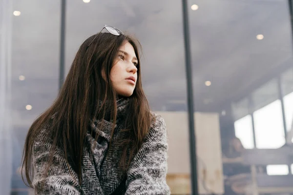 Стильная длинноволосая девушка в сером пальто, наслаждающаяся облачной погодой, уличным стилем — стоковое фото
