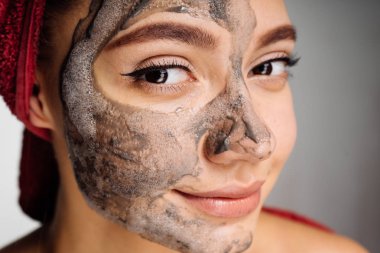 güzel bir genç kız için yarım yüz yararlı kil maskesi uygulanmış, güzel olmak istiyor