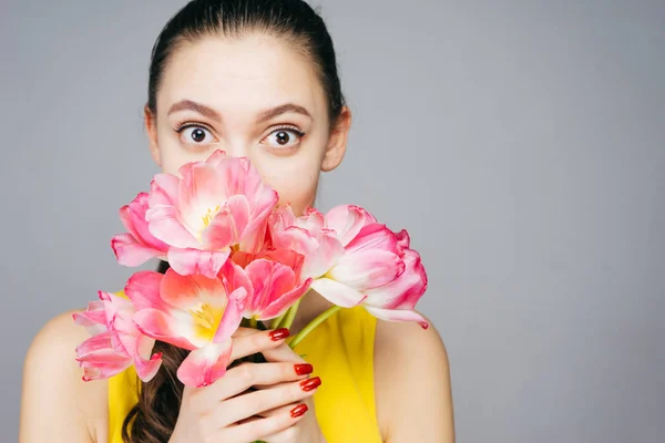 Linda joven sorprendida, sosteniendo un ramo de flores rosadas fragantes — Foto de Stock