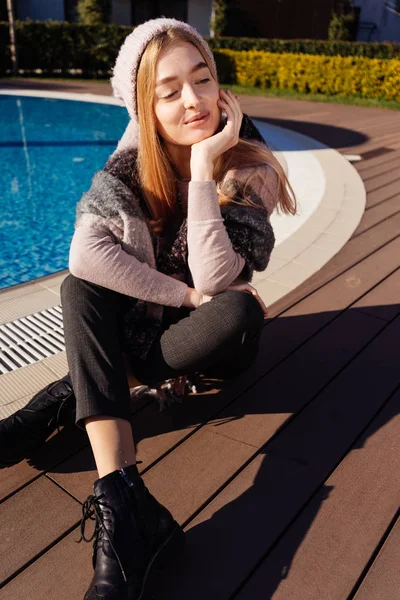 Bella bella ragazza siede vicino alla piscina blu, sorridente, ai raggi del sole — Foto Stock