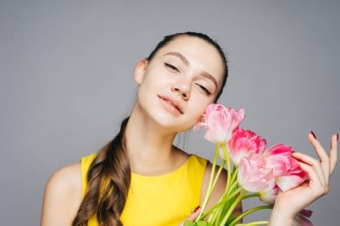 bir buket kokulu Pembe çiçek tutan güzel genç kadın bahar havanın tadını bir sarı elbiseli