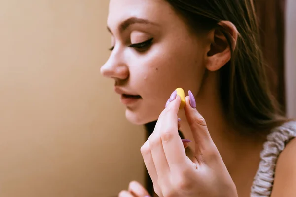 Una giovane ragazza assonnata vuole dormire, si inserisce nelle orecchie tappi gialli contro il rumore della strada — Foto Stock