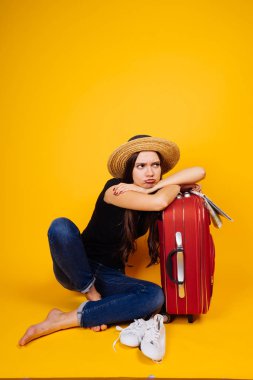 üzgün genç kız büyük bir bavul yanında oturan tatilde bir yolculuğa çıkıyor