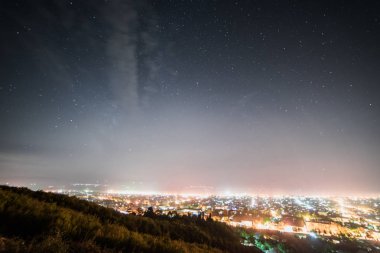 yukarıdan bir görünümü üzerinde bir büyük parlak şehir ışıkları parlayan ve ışıklar yanıyor, gece yıldızlı gökyüzü altında