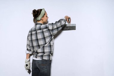 bir duvar bir spatula ile tesviye, tamir ekose gömlekli çalışkan genç kadın