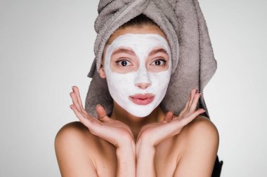 sevimli genç kız başında bir havlu ile yararlı bir beyaz maske yüzünde bir spa yordam uygulanan
