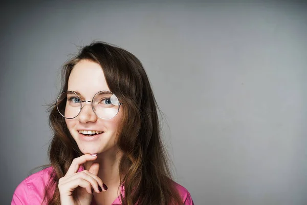 Feliz joven trabajadora de oficina en una camisa rosa y gafas sonriendo — Foto de Stock