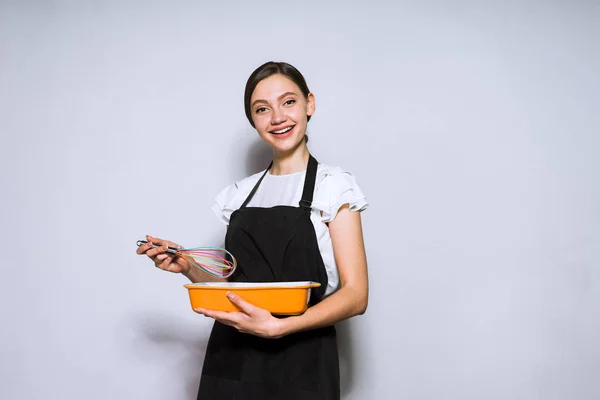 Щаслива молода жінка шеф-кухаря в чорному фартусі готує смачну страву на вечерю — стокове фото