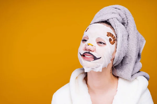 Rolig tjej med en handduk på huvudet leende, på ansiktsmask med hund ansikte — Stockfoto