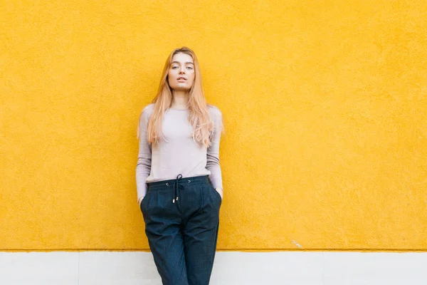 Jonge blonde model meisje in modieuze kleding poseren op gele muur achtergrond, Streetstyle — Stockfoto