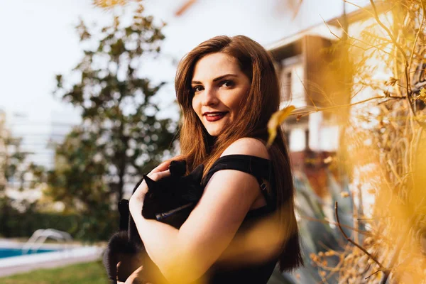 parkta yürüyüş, siyah bir kedi holding ve gülümseyen çekici uzun saçlı genç kadın