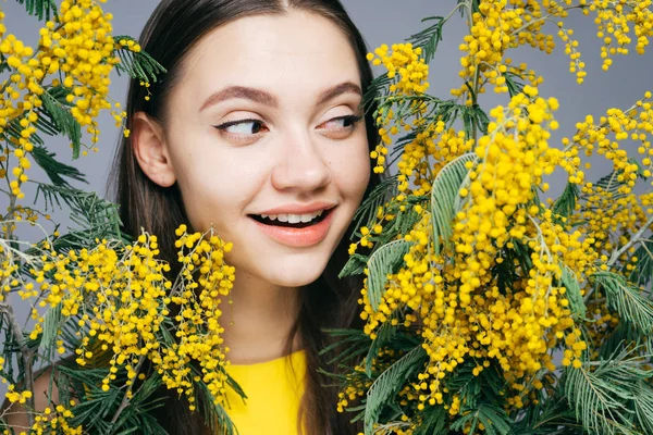 Heureuse jeune fille jouit d'un mimosa jaune parfumé, le temps du printemps — Photo