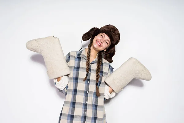 Fröhliches junges Mädchen aus Russland mit warmer Pelzmütze freut sich im Winter, hält warme Filzstiefel — Stockfoto