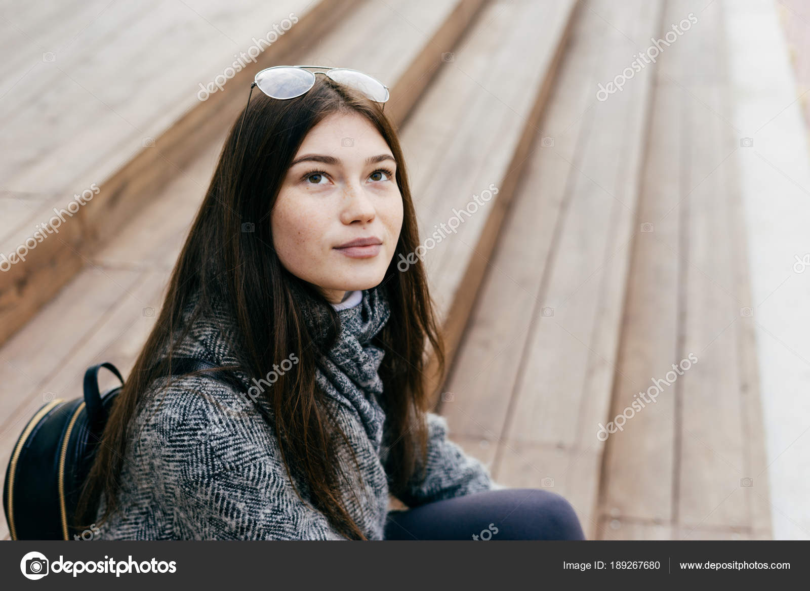 Cute Dark Haired Girl In Gray Coat Sits On Steps In The Open Air
