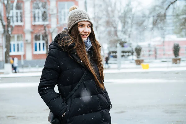 Cute girl długowłosy w ciepłą kurtkę spacery po ulicach miasta w zimowej pogodzie, uśmiechając się — Zdjęcie stockowe