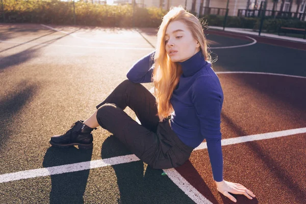 Молода красива блондинка позує на спортивному полі на ранковому сонці — стокове фото