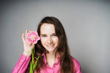 pembe gömlek gülümseyen ve bir çiçek tutan kadın