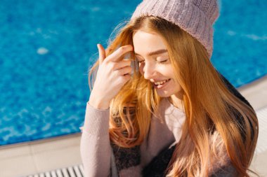 Mavi havuzun kenarında oturan sarışın kız modeli