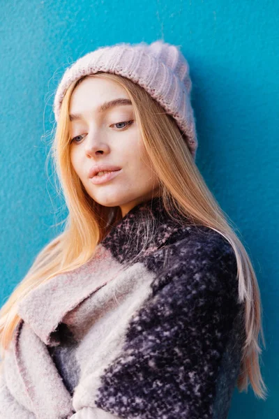 Красивая молодая блондинка позирует против синей стены на открытом воздухе, на плечах теплый носовой платок — стоковое фото