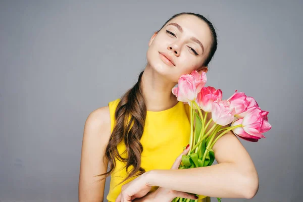 Menina atraente em vestido amarelo detém um grande buquê de flores rosa perfumadas, goza de primavera — Fotografia de Stock