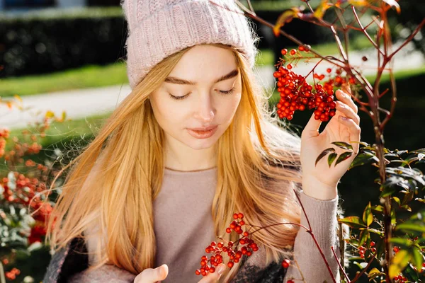 Carino giovane ragazza bionda in cappello passeggiando in giardino, godendo la natura e il sole, primavera — Foto Stock