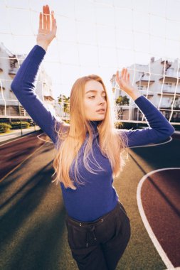 Mavi kazaklı spor sahasında poz şık genç kız modeli