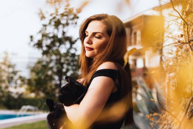 siyah bir kedi, güneş ışınlarının bir bahçede tutan bir lüks uzun saçlı kız