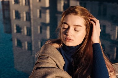 açık havada, güneş, mavi havuz kenarında oturan güzel kız sarışın model gözleri kapalı