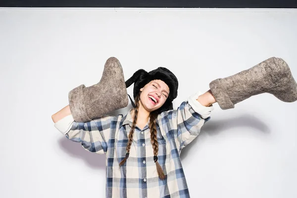 Lustig fröhliches russisches Mädchen mit Pelzmütze freut sich im Winter, hält warme Filzstiefel — Stockfoto