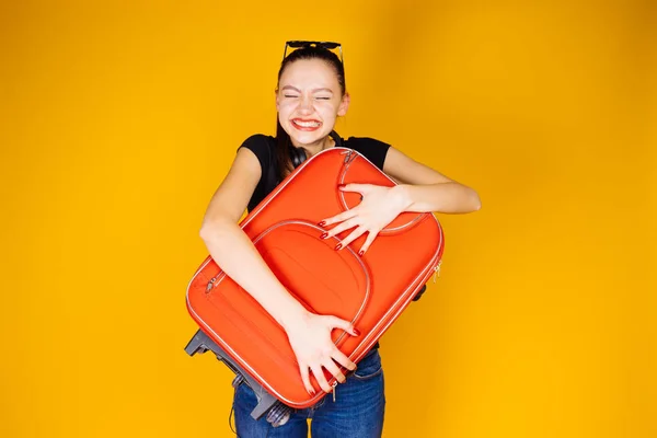 Счастливая молодая девушка отправляется в путешествие, отпуск, держит большой красный чемодан — стоковое фото
