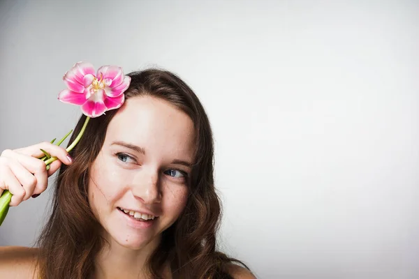 Bonito menina de olhos azuis sorrindo, segurando uma flor rosa perfumada — Fotografia de Stock