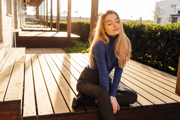 सुंदर लड़की ब्लू स्वेटर में सुनहरे बालों वाली मॉडल सूरज में पार्क में पोज़िंग, आंखें बंद — स्टॉक फ़ोटो, इमेज