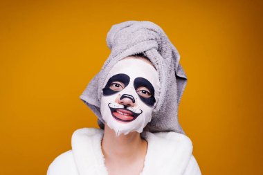 gülümseyen yüz maskesinin bir panda namlu ile üzerinde başında bir havlu ile mutlu kız