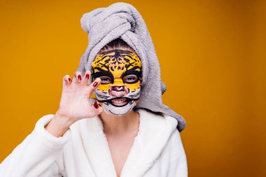 genç kız başında bir havlu ile bir canavar, growls, yüzünde bir maske bir leopar bir suratla gösteriyor