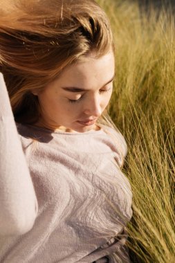 sevimli genç sarışın kız açık havada poz, gözleri kapalı sıcak bahar hava ve güneş, zevk