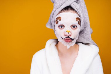 sevimli genç kız kendini bir havlu başında, bir hayvanın yüzünü yüzündeki maskeyle önem verdiği