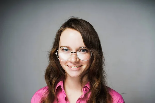 Bela jovem trabalhador de escritório em uma camisa rosa e óculos sorrindo e olhando para a câmera — Fotografia de Stock