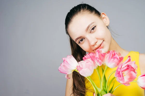 Gülümseyen ve bahar zevk güzel genç kız sarı elbiseli bir buket çiçek, holding — Stok fotoğraf