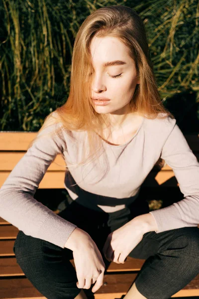 Mooie jonge blonde meisje poseren buiten in de zon, de ogen gesloten — Stockfoto
