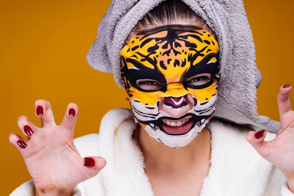 Drôle jeune fille avec une serviette sur sa tête grogne, masque facial avec visage léopard — Photo