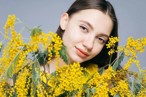 Atractiva jovencita disfrutando de la primavera, sosteniendo un ramo de mimosa amarilla — Foto de Stock