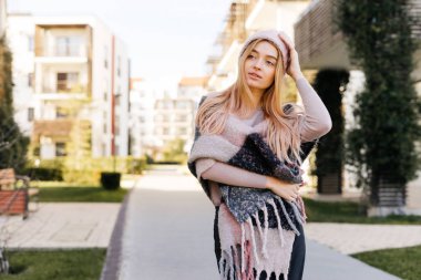 Bahar havanın tadını bir güzel sarışın kız bir şapka ve şehrin sokaklarında yürürken bir eşarp