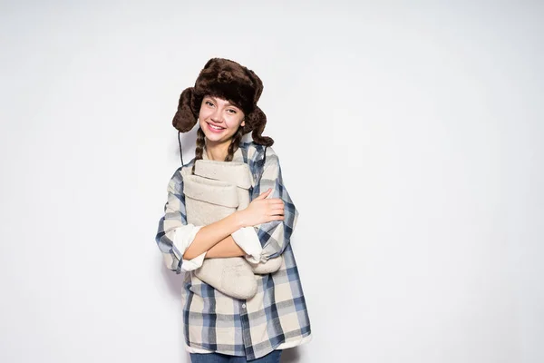 Hermosa joven rusa chica en cálido sombrero de piel sostiene cálido invierno fieltro botas y sonrisas — Foto de Stock