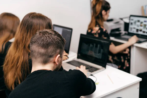 Meninas e um cara, designers gráficos, trabalhando em um projeto em laptops no escritório — Fotografia de Stock
