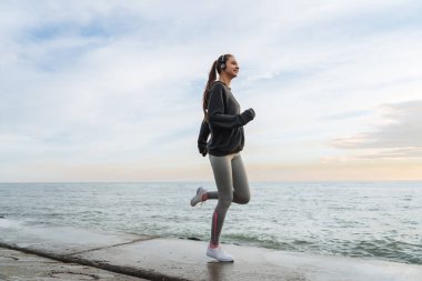 atletik genç kız giyen kulaklık, motivasyon, çok açık egzersiz için enerji Denizi çevresinde çalışan